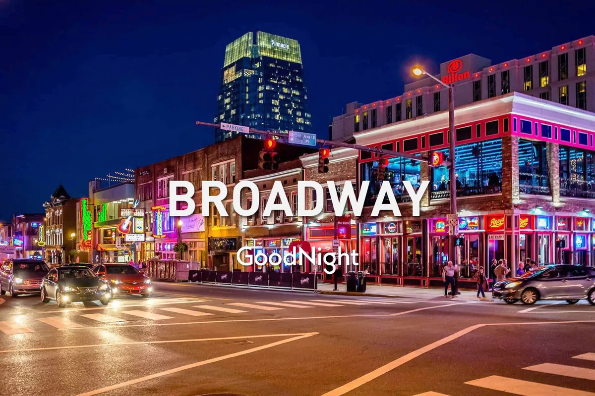A bustling urban street scene with neon signs, high-rise buildings, busy sidewalks filled with people, and the unmistakable nighttime energy of Nashville’s downtown nightlife.