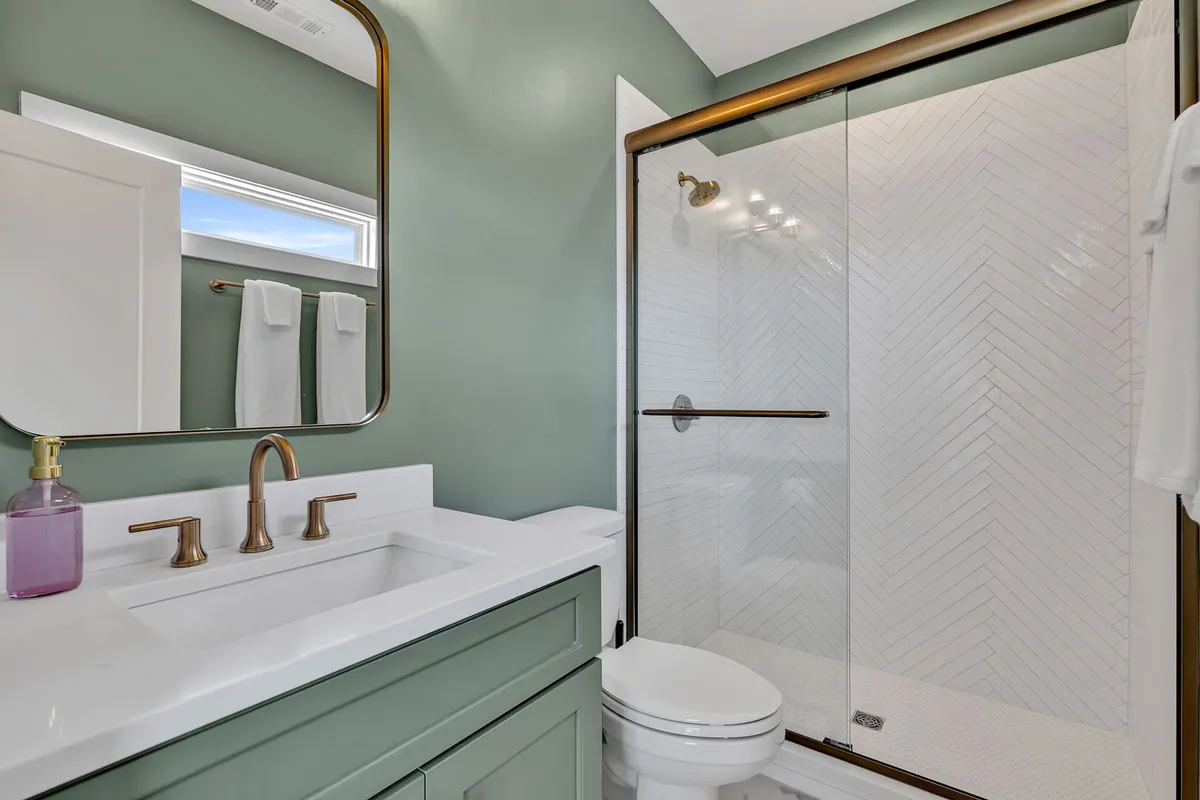 A modern bathroom with a vanity and sink, a spacious shower area, and a large mirror. The space feels calm and contemporary, ideal for relaxation and personal routines.