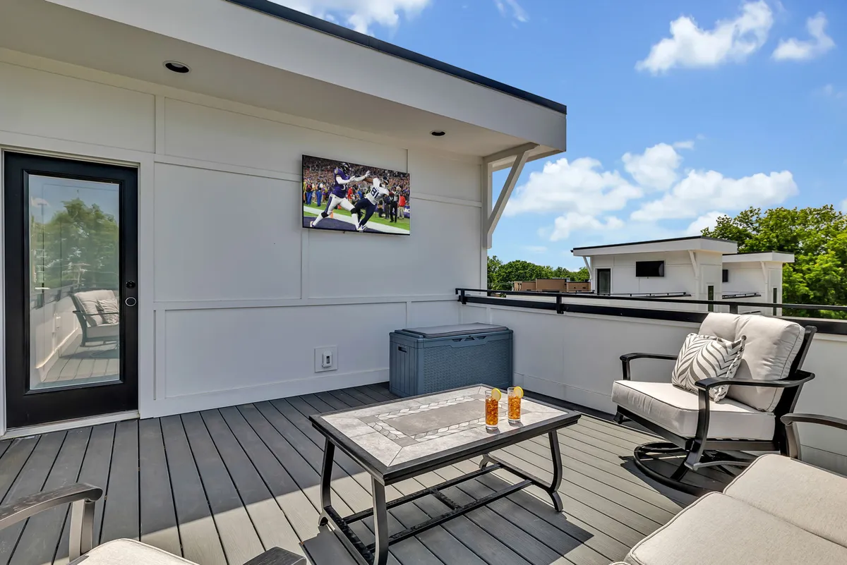 A stylish rooftop outdoor seating area equipped with a television, comfortable furnishings, and a coffee table. The scene includes cityscape views beyond the rooftop, creating a lively atmosphere for group gatherings or brainstorming sessions with a view.