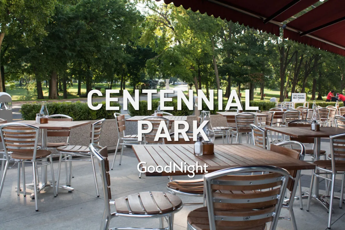 This exterior scene highlights a relaxed outdoor dining area with wooden tables and lush greenery in the background. The ambiance is casual and social, evoking the feel of local cafes and seasonal outdoor experiences.