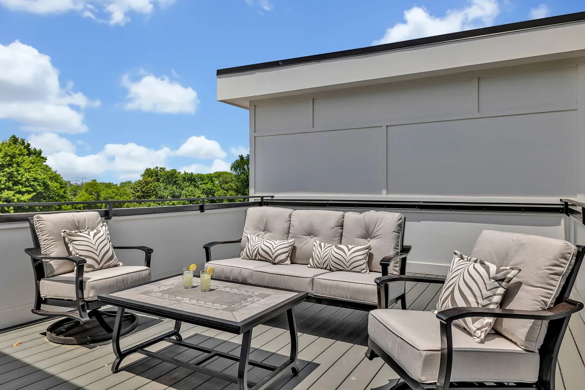 An inviting outdoor seating arrangement on a private rooftop or patio, complete with decorative cushions and a coffee table—perfect for sunset drinks, stargazing, and brunches. The mood is welcoming and relaxed.